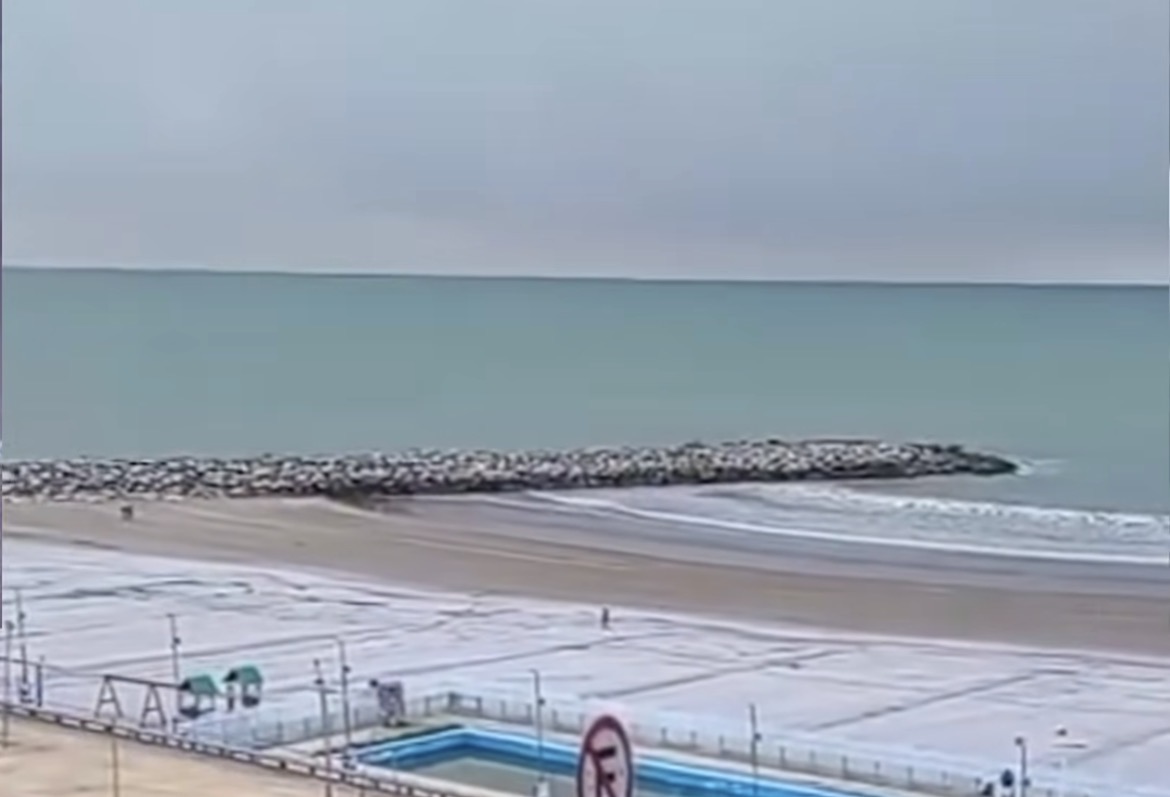 Χιονισμένη παραλία στο Mar del Plata της Αργεντινής, με τη θάλασσα και κυματοθραύστη στο βάθος